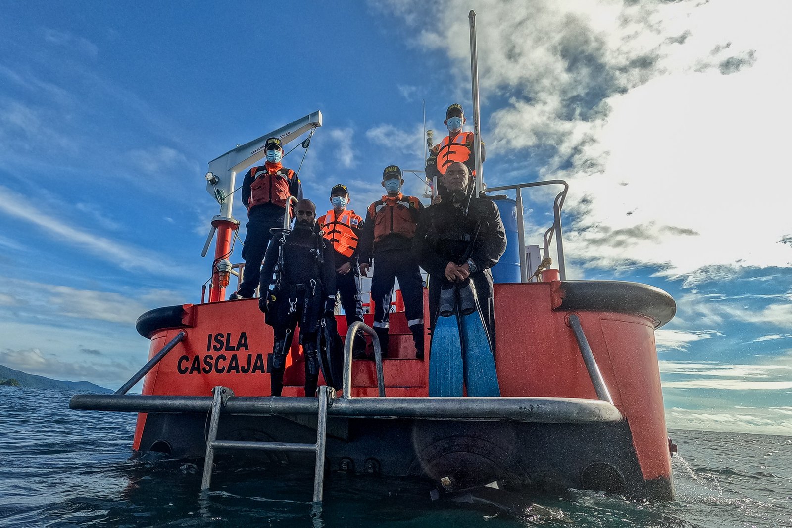 Jalvan standing on the stern of the vessel 'Isla Cascajal' alongside the Colombian Coast Guard crew during a humpback whale rescue operation.